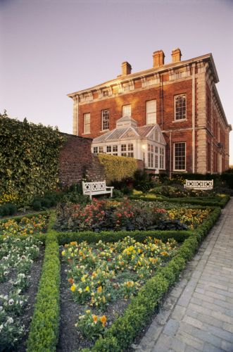 The West front of Beningbrough Hall showing the formal flower beds and the conservatory lit by a warm afternoon light. Image reference 8319. ©National Trust Images/Ian Shaw. www.nationaltrust.org.uk