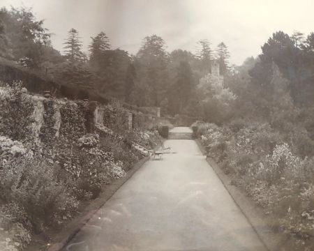 Old photograph showing path with flower borders to either side and viewing tower in the distance