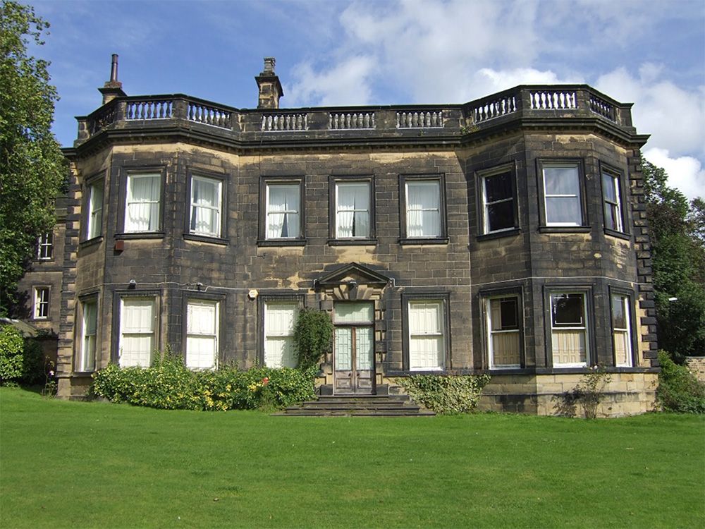 A facade of a large Georgian-style building built in dark stone.