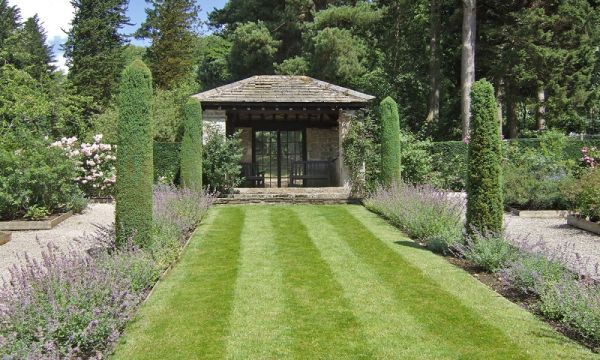 A well-tended garden and lawn lead up to a stone-built seating area at Parcevall Hall.