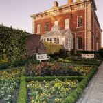 The West front of Beningbrough Hall showing the formal flower beds and the conservatory lit by a warm afternoon light. Image reference 8319. ©National Trust Images/Ian Shaw. www.nationaltrust.org.uk